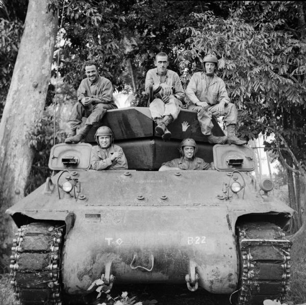 Tank crew at Saidor, New Guinea (present day Papua New Guinea). The soldier's names are, (top, left to right) Corporal Jim Malliares of Lowell, Massachusetts, Corporal John Binkham of Woolwich, Maine, Sergeant John Rees of Waukesha, Wisconsin, (hatch, left to right) Corporal Franklin Rupnow of Oconomowoc, Wisconsin and Corporal Edward Gaudette of Nashua, New Hampshire. The tank has some art painted on the turret of a hand, and a devil's head with horns with the number 2 painted on it, on the upper right. Trees are in the background.