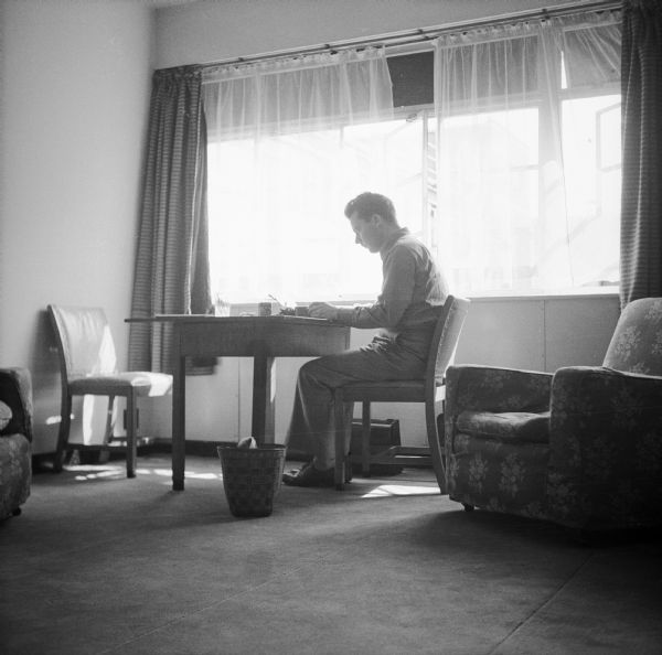 Robert Doyle in his room in London, England, at the Mount Royal Hotel. He is working at his typewriter in front of the window.