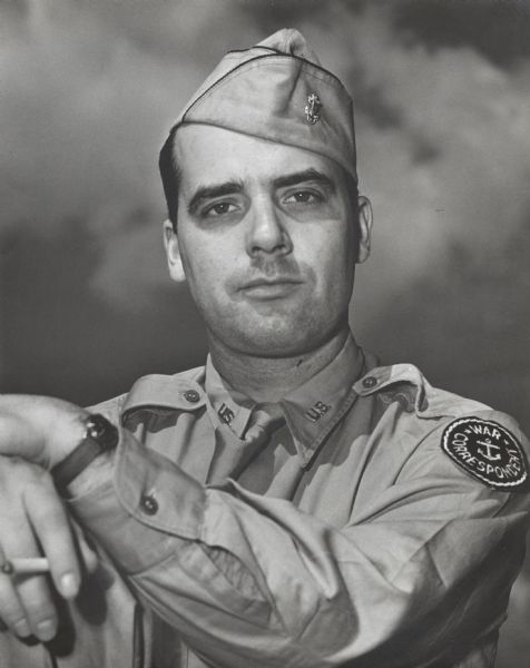 Quarter-length portrait of Robert Doyle, dressed in his uniform. His arms are resting casually on his right knee and he is holding a cigarette. Doyle was a civilian war correspondent for the <i>Milwaukee Journal</i> during World War II, covering the experiences of Wisconsin troops in the 32nd "Red Arrow" Division, an infantry division of the United States Army National Guard. The "Red Arrow" Division consisted mainly of soldiers from Wisconsin and Michigan.