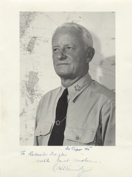 An autographed quarter-length portrait of Fleet Admiral Chester William Nimitz in his office at CinCPac/CinCPOA Advanced Headquarters on Guam. He is standing in front of a map of the Pacific Ocean. The left side of the map is showing China, Taiwan and the Philippines. Nimitz is wearing a uniform shirt and tie with the five star insignia on his collar and on his tie clasp. The tie clasp was a gift. At the bottom of the photograph is written: "30 Apr 45, To Robert Doyle, with best wishes, C.W. Nimitz." On March 30th, 1942, the newly-formed US-British Combined Chiefs of Staff appointed Nimitz as Commander in Chief, Pacific Ocean Areas with operational control over all Allied units (air, land, and sea) in that area. Admiral Nimitz was promoted to Fleet Admiral of the United States Navy on December 15th, 1944.