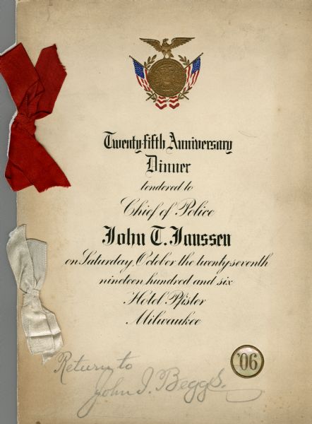 Front cover of the program and menu for the twenty-fifth anniversary dinner for Chief of Police John T. Janssen at the Hotel Pfister. At the top is an eagle with outstretched wings perched atop the seal of the city of Milwaukee, superimposed on two crossed American flags and a laurel wreath. A mother-of-pearl medallion imprinted with a raised "'06" is in the lower right-hand corner. The program is bound with two silk ribbons; one red and one white.