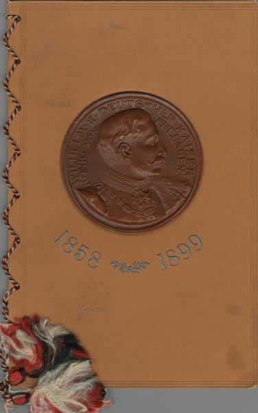 Front cover of the menu for the "Fest-Mahl zur Feier des Geburtstages" given to Wilhelm II in Frankfurt, with a brown leather medallion embossed with a head and shoulders profile portrait and the words "Wilhelm II Deutscher Kaiser Konig von Preussen." The dates 1858 and 1899 appear in silver-colored raised printing beneath the medallion on light brown card stock bound with a tri-colored twisted silk cord with tassels.