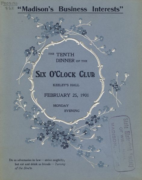 Front cover of the announcement for a Six O'Clock Club Dinner on the topic, "Madison's Business Interests," with an embossed scrolling silver frame adorned with sprays of blue flowers with silver stems. Text printed in dark blue ink on blue card stock.