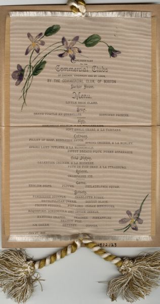 Menu for a dinner at the Parker House, given by the Commercial Club of Boston for the Commercial Clubs of Chicago, Cincinnati, and St. Louis. Imprinted on fringed silk adorned with hand-painted flowers at the upper left and lower right corners. A gold and ivory twisted and tasseled cord is attached at the top and bottom.