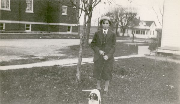 Willard Nuss, holding a small dog on a chain leash, poses near Peace Evangelical and Reformed Church in Potter. He was the "leader of the highest class in math" at the Potter School, District No. 3.
