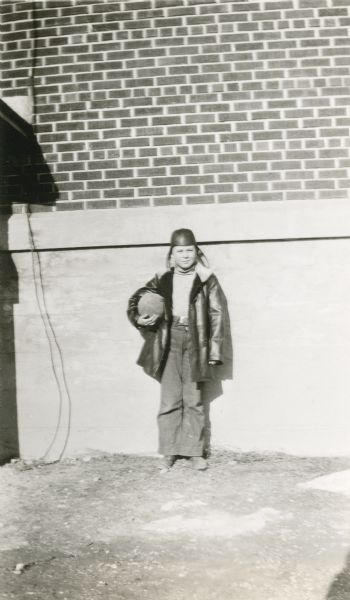 Elliot Wenzel, age 11, poses for his photograph as the "Leader in Play" at the Potter School, District No. 3. He holds a football and wears a leather hat similar in style to the football helmets of the time. His teacher described him as an "average student, very active in all boys' games."
