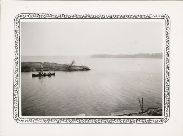 View from shoreline of three men in a canoe on Lake Menomin near a point of land.