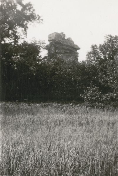 A view of Pompey's Pillar, a rock formation four miles northeast of Highland. Written on the reverse of the photograph: "It is 150 feet high from the base and has a diameter of about 35-40 feet. Scenery around this rock is very beautiful. With difficulty, the rock may be ascended."