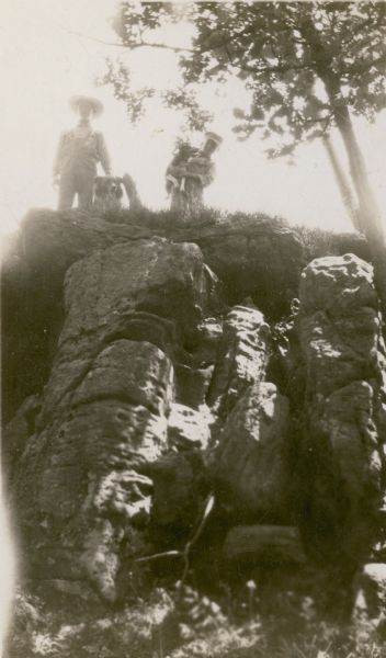 View looking up at two boys with two dogs posing atop a bluff at the Charles Gottschall farm.