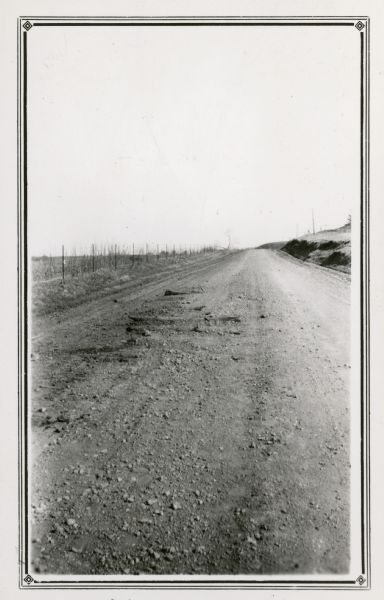 Several old timbers are exposed on Mud Branch Road. A one-mile stretch of the road was originally constructed as a corduroy road because of "quick sand" in the area. On the reverse of the photograph is written "The winter freeze and spring thaw always bring some [timbers] to the surface."