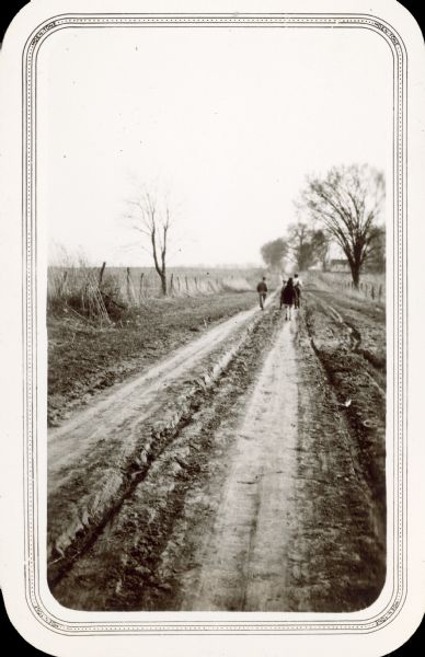 Four children walk away from the photographer down a rutted one lane road. On the reverse is written, "One of the oldest roads in [Richland] county, leading to the old tye landing on the Wisconsin River west of Muscoda and a mile from the Eagle Corners School."