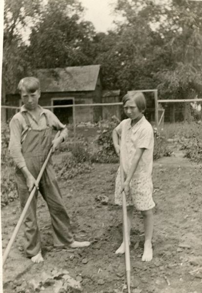 Earl Woodbury, 14, and his sister Helen, 12, work barefoot in the garden of their home farm. Both are students at the Cloverland School, District No. 2. There is an outbuilding in the background.