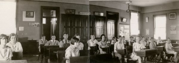 Students at Rhine Center School pose at their desks for a group portrait. Most of the boys are wearing neckties. Twins Herbert and Norbert Hornbeck, 13, are seated in the last seats of the second row from the left.