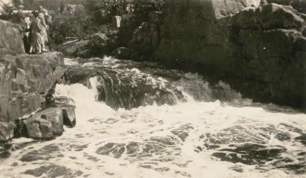 A group of people stand on a ledge overlooking Copper Falls.