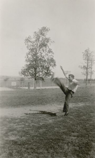 Felix Liburdi, age 17 and a student at the Hillcrest School, District No. 6, Towns of Waukesha, Pewaukee, Brookfield and New Berlin, demonstrates his kicking form. The son of Italian immigrants Petro and Annie Liburdi, Felix is described on the reverse of the photograph as "Exceedingly well developed; has fixed up a gymnasium in his home; runs 2 miles every day in summer time; referees school basketball and football; won county athletic honors for 2 years at county field meet; fine scholar."