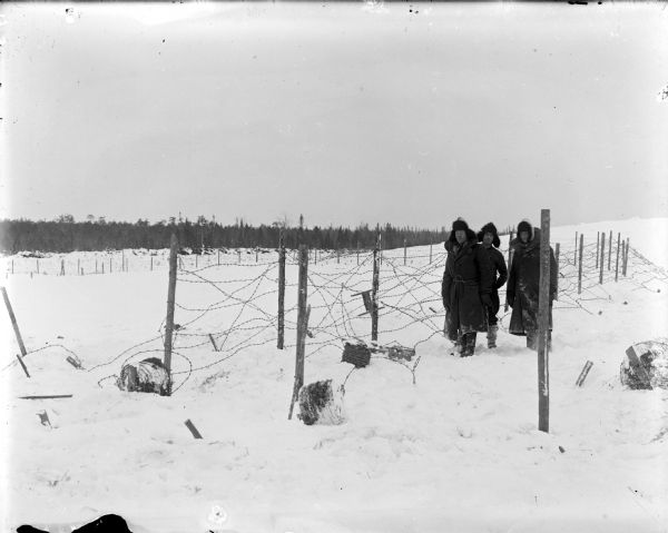 Three soldiers installing barbed wire as a defense against Bolshevik forces.