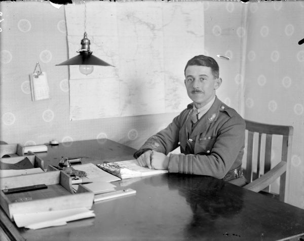 Portrait of Lieutenant Colonel Stokes, the commanding officer of the Corps of Royal Engineers, in uniform and sitting at his desk.
