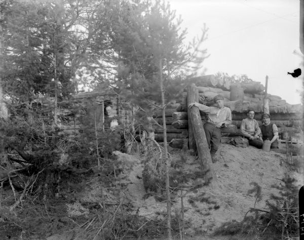 Four soldiers standing around a bomb-poof shelter, which received four direct hits from Bolshevik artillery without any damage.