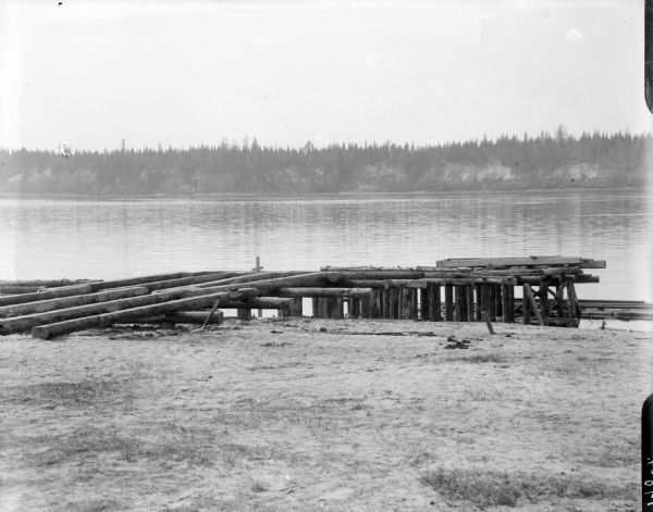 View from shoreline of a dock constructed of timbers at Ust Pinega in Russia. It is located downstream from Archangel [Archangelsk], Russia where the Pinega and Dvina Rivers meet.