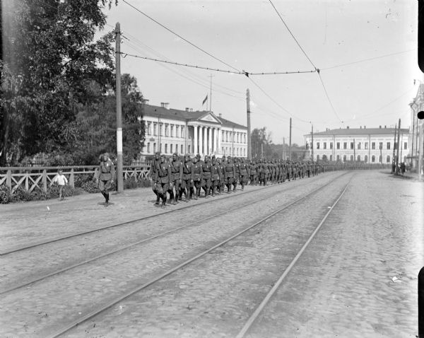 View down street of an approaching column of American officers and soldiers parading through the downtown of Archangel [Archangelsk], Russia.