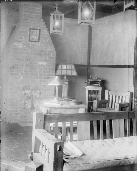 Interior view of the officers quarters of the 310th United States Engineers. On the far wall is a stone fireplace which displays a portrait of General John Pershing. In the foreground is a wooden bench, and behind it is a table with a table lamp. There is a floor lamp near the fireplace, and two lamps hang from the ceiling. In the corner is a record player sitting on a cabinet that holds stacks of records.