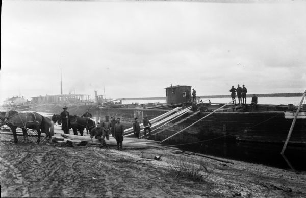 Soldiers from the 310th U.S. Army Engineer Corps unloading lumber from barges.