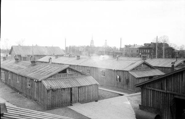 Barracks used by United States Army Engineer Corps, 310th Regiment, Company C, with clothes on the roof and hanging on the side of the building. In the background are churches and other buildings.
