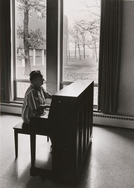 Miss Lydia Henie, 76 years old, playing the piano in the devotional room of the Home for Aged Lutherans, 7500 West North Avenue. 
