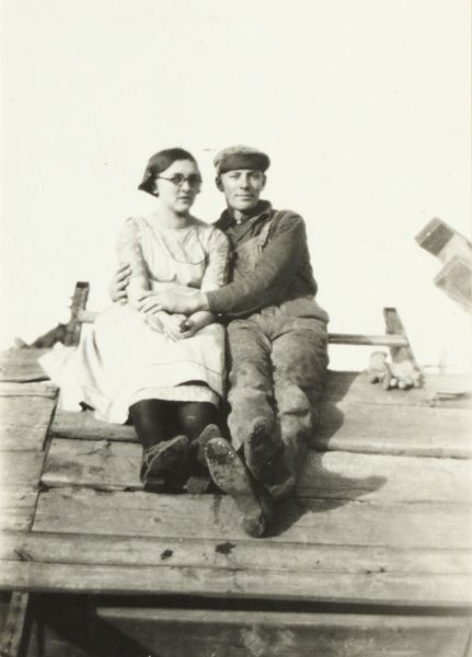 Couple sitting on roof which is under construction.