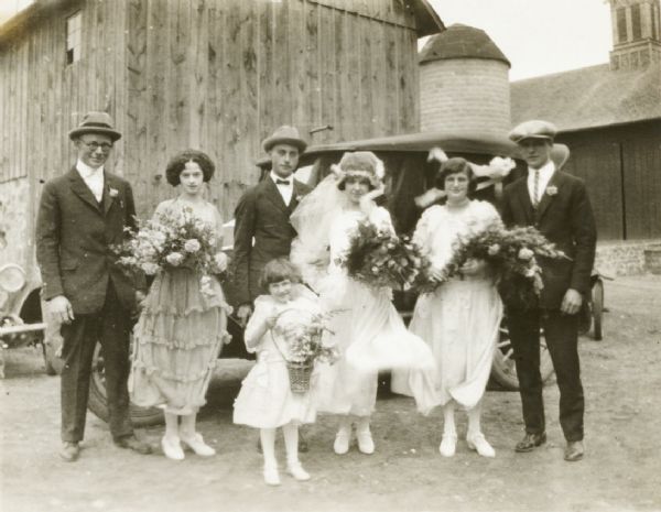 Wedding party posing in a barnyard.