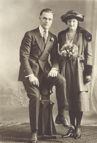 Studio portrait in front of a painted backdrop of a couple, probably  newlyweds.