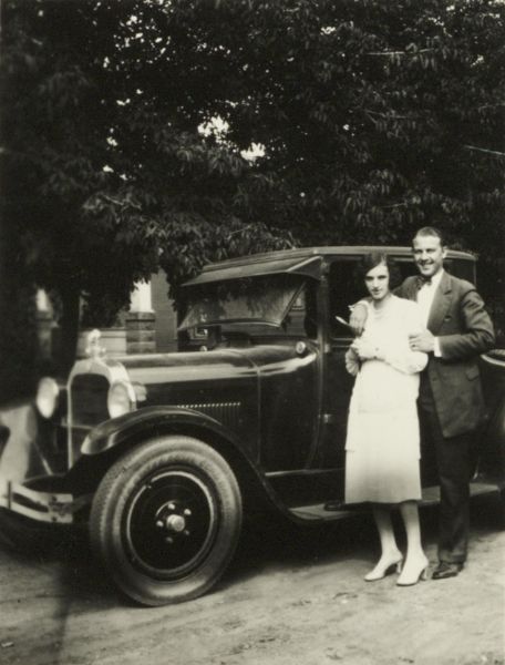 Young couple standing in front of a Dodge coupe.
