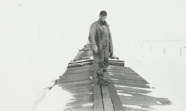 Railroad man standing on top of train of snow-bound freight cars.