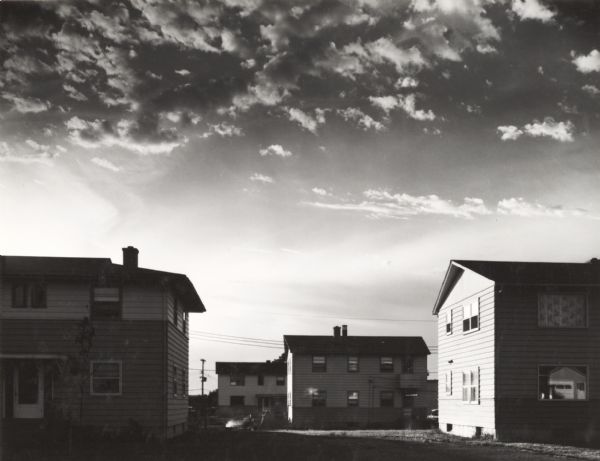 Scene with duplex houses and clouds at sunset.