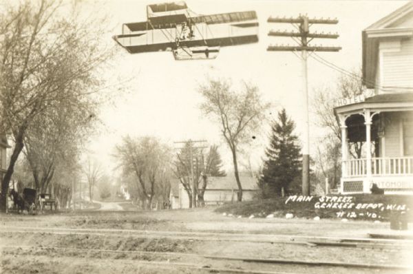 Street in Genesee Depot, with superimposed biplane flying low overhead.
