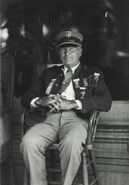 Seated portrait of an elderly army man, partially in uniform, with medals on his jacket.