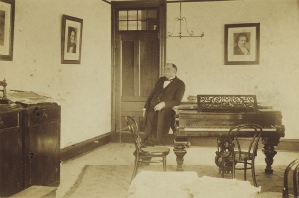 Professor Hood, head of the music department at Rockford College, leaning on a piano.