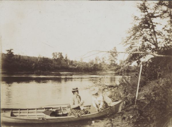 Two girls in a boat at the shoreline of the Black River.