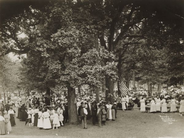 Scene in a small city park showing a group of local women serving luncheon to soldiers recently returned from service in the first World War. Very possibly a Walworth County unit recently returned from service.