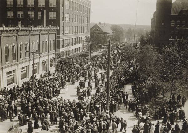 Elevated view of street entertainment, with crowds, dancing and band concert to welcome home Wisconsin National Guard, 3d Regiment, Company H, after service in the first World War.