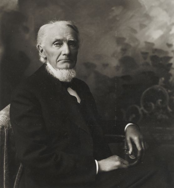 Seated studio portrait in front of a painted backdrop, retouched, of J.H. Denison.