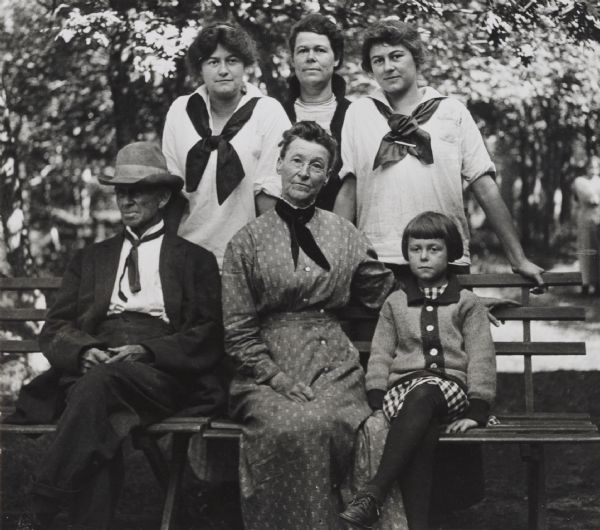 Outdoor group portrait of the Ashmun family posed on and behind a bench. C.S. Ashmun, Jane Ashmun and Isabel Ashmun Roberts are seated on the bench, while Alice Ashmun, Mary Ashmun Roberts, and Louise Ashmun are standing behind.