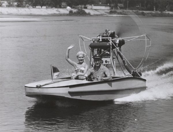 Young couple riding in a hydroplane speedboat.