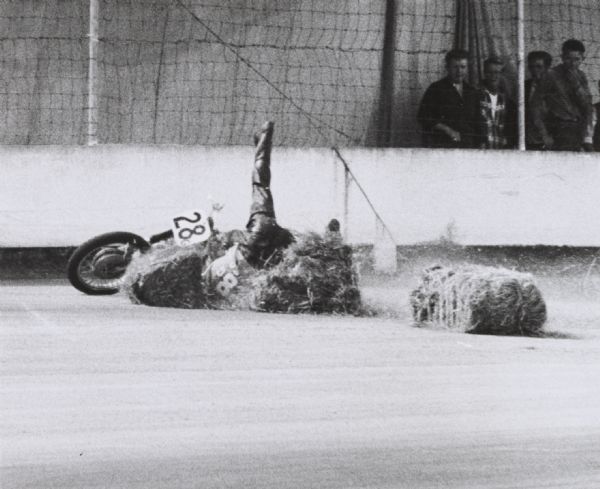 Motorcycle race contestant overturned on the track after collision with haybales.