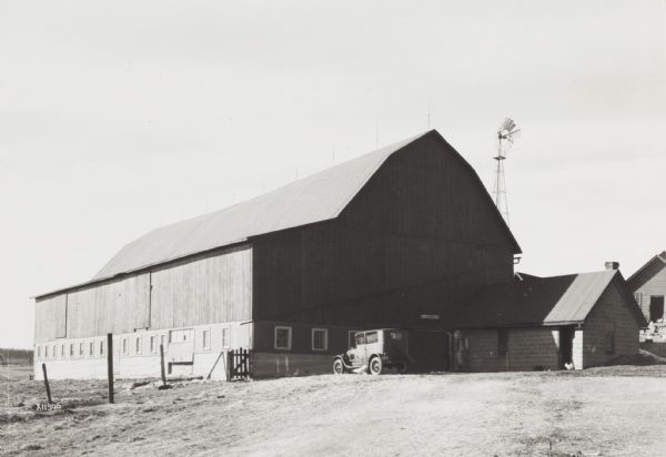Exterior of a large barn and automobile.