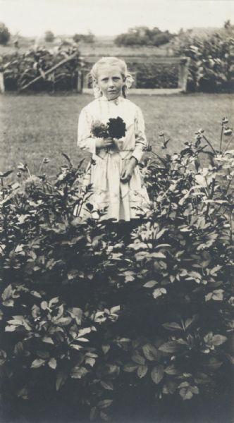 Young girl holding flowers, in a flower garden.