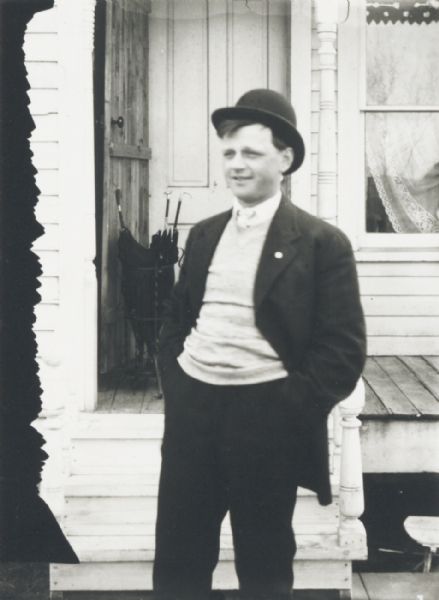 Young man standing in front of a house porch.