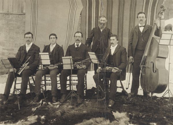 Quintet of chamber musicians posed in barnyard.