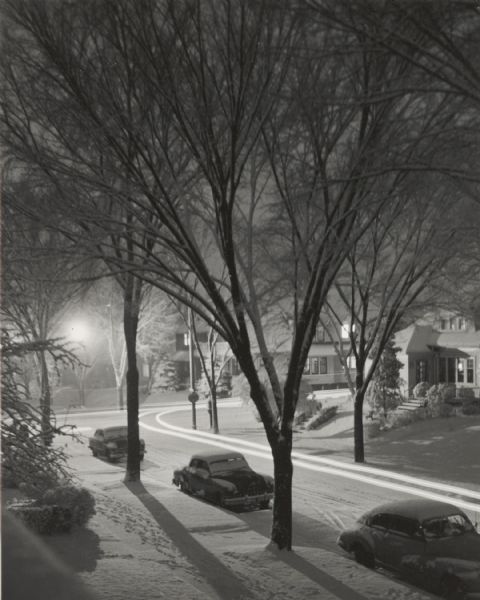 Winter scene of a Milwaukee residential street corner with snow at night.