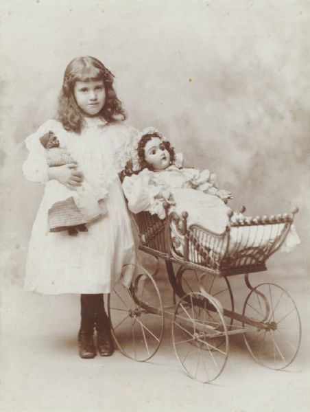 Studio portrait of a young girl with two dolls.